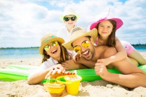 Junge Familie, die sich im Urlaub am Strand auf grüner Luftmatratze freut